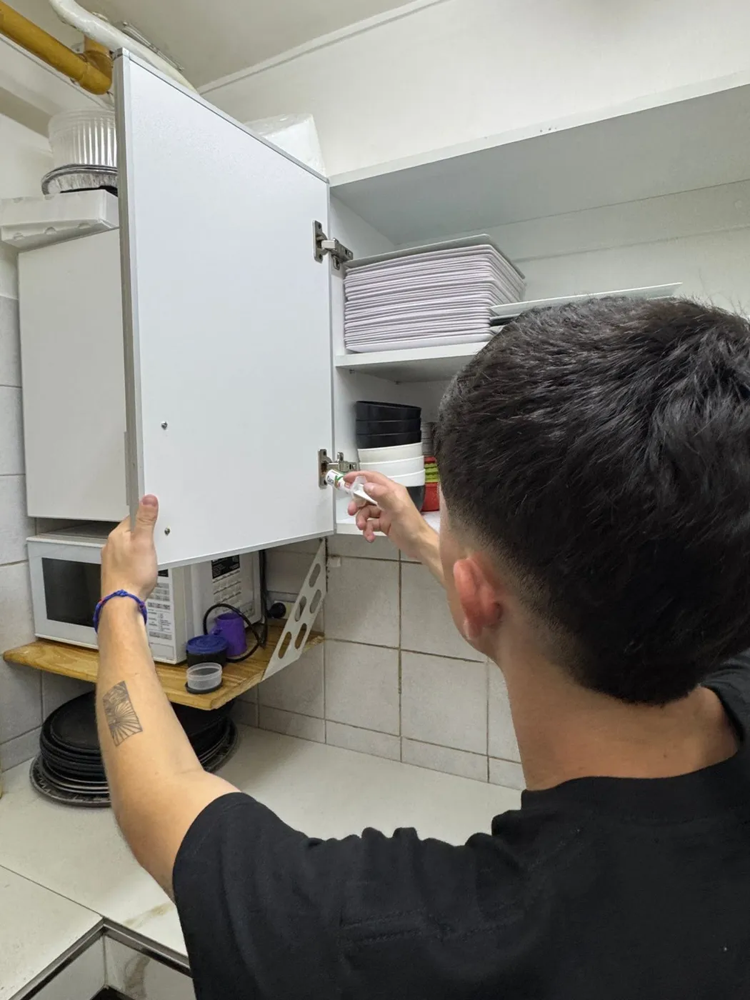 Técnico de Vámonos Pest aplicando gel contra cucarachas en las bisagras de una alacena