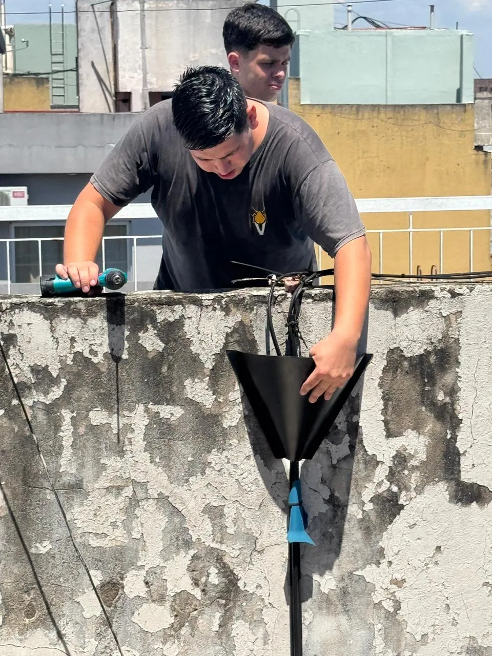 Técnicos de Vámonos Pest colocando un cono protector en los cables de una azotea para que no suban roedores