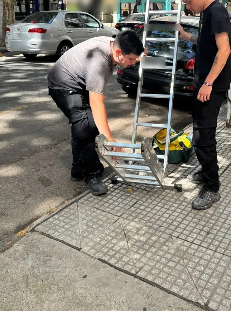 Dos técnicos de Vámonos Pest preparando la escalera en la vereda