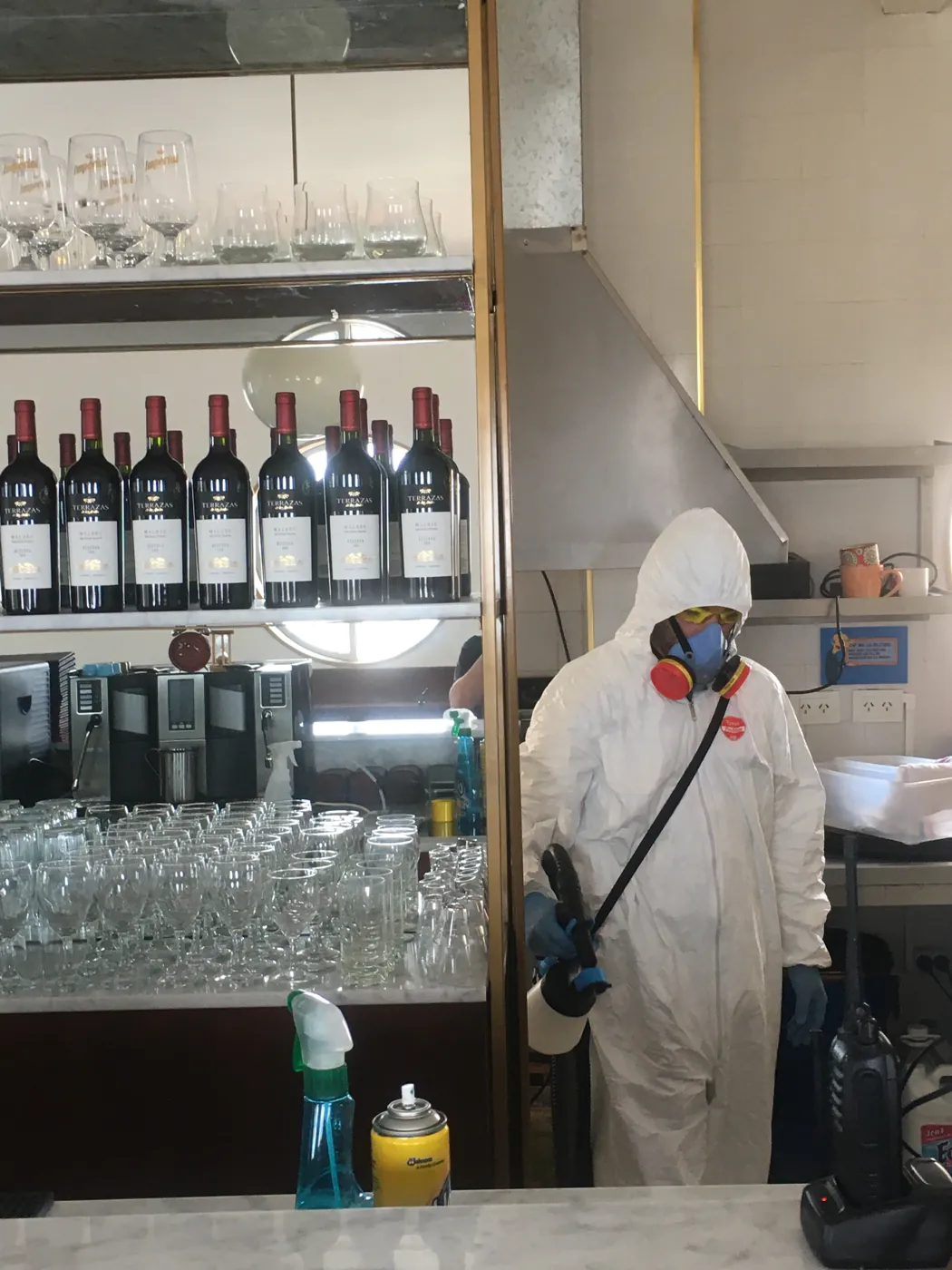 Técnico de Vámonos Pest con traje de protección desinfectando la barra de un restaurante